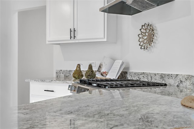 details featuring white cabinets, exhaust hood, light stone counters, and range