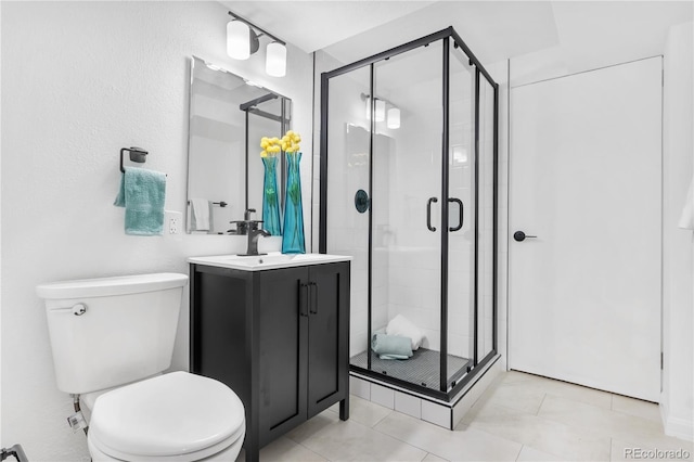 bathroom with tile patterned floors, toilet, a shower with door, and vanity