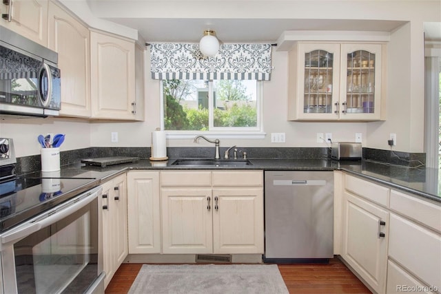 2935 Bow Line Pl, Longmont, CO 80503 - kitchen with stainless steel appliances, a sink, dark wood-style floors, and glass insert cabinets