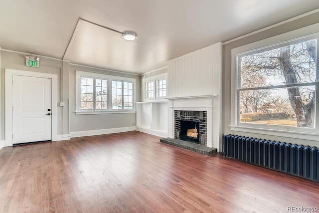 1602 11th Ave, Greeley, CO 80631 - unfurnished living room featuring radiator, wood finished floors, and a brick fireplace