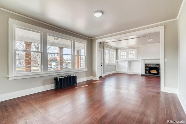1602 11th Ave, Greeley, CO 80631 - unfurnished living room with radiator heating unit, crown molding, a brick fireplace, and dark wood-style floors