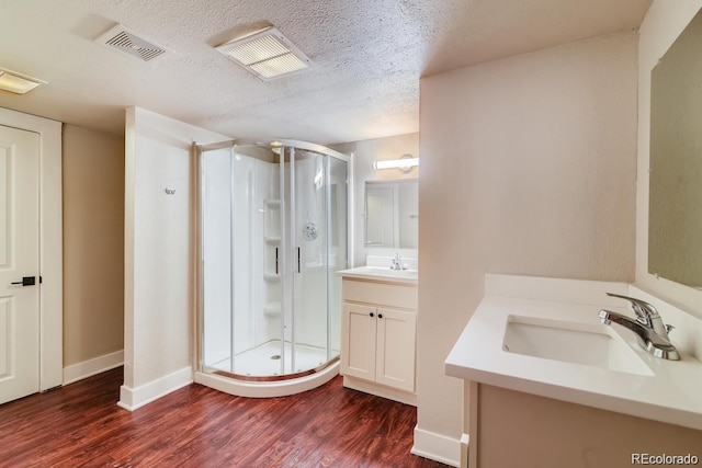 1602 11th Ave, Greeley, CO 80631 - bathroom featuring a shower stall, wood finished floors, two vanities, and a textured ceiling