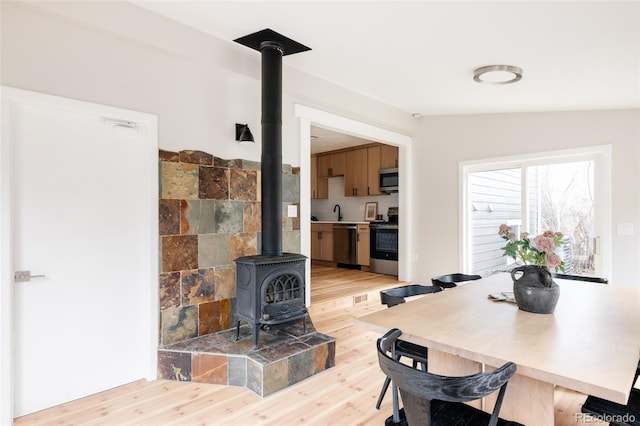 dining area featuring a wood stove and light wood-type flooring