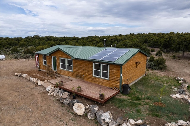 3130 Elk Park Rd, San Luis, CO 81152 - back of property with roof mounted solar panels, metal roof, a deck, and a forest view