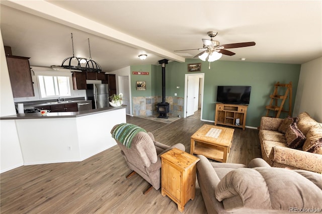 3130 Elk Park Rd, San Luis, CO 81152 - living room featuring a wood stove, beamed ceiling, wood finished floors, and a ceiling fan