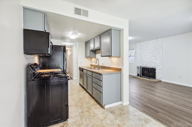 kitchen with gray cabinets, sink, black appliances, and light hardwood / wood-style floors