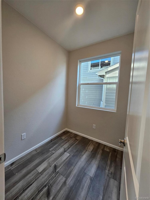 spare room with dark wood-type flooring and baseboards