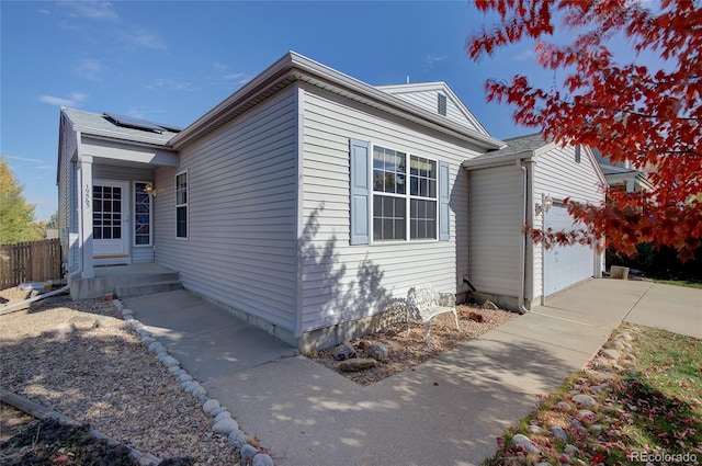 view of home's exterior featuring solar panels, concrete driveway, an attached garage, and fence