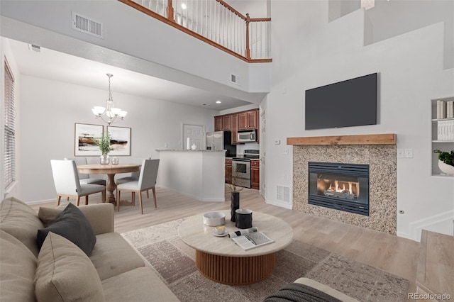 7777 E 23rd Ave Unit 1406, Denver, CO 80238 - living area featuring light wood-type flooring, a chandelier, baseboards, a fireplace, and a high ceiling