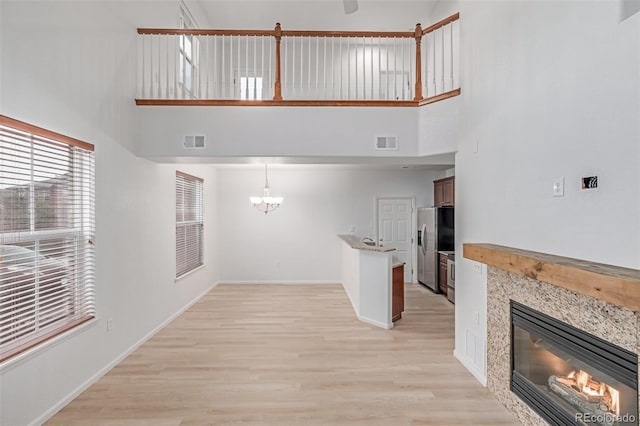 7777 E 23rd Ave Unit 1406, Denver, CO 80238 - unfurnished living room with a high ceiling, a glass covered fireplace, a chandelier, light wood finished floors, and baseboards