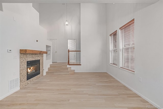 7777 E 23rd Ave Unit 1406, Denver, CO 80238 - unfurnished living room with a towering ceiling, a tile fireplace, light wood-type flooring, baseboards, and stairs