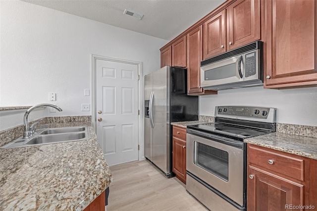 7777 E 23rd Ave Unit 1406, Denver, CO 80238 - kitchen featuring stainless steel appliances, a sink, light wood finished floors, light countertops, and brown cabinetry