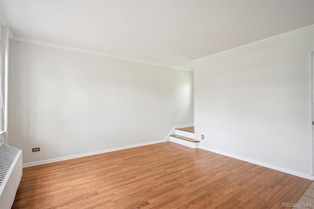 empty room featuring ornamental molding, stairs, radiator, baseboards, and light wood-type flooring