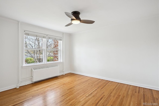 empty room featuring ceiling fan, ornamental molding, radiator heating unit, and light wood-style floors