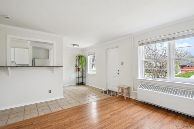 foyer featuring baseboards, ornamental molding, light tile patterned floors, and radiator heating unit
