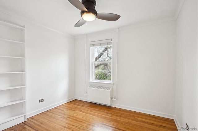 spare room with ornamental molding, baseboards, ceiling fan, radiator heating unit, and light wood-style flooring