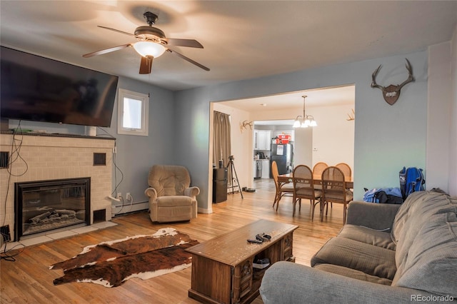 living room with a fireplace, ceiling fan with notable chandelier, light hardwood / wood-style flooring, and baseboard heating