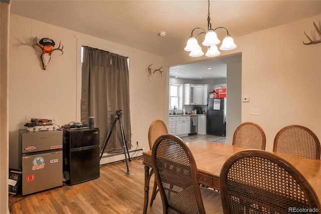 dining space featuring an inviting chandelier, sink, light wood-type flooring, and baseboard heating