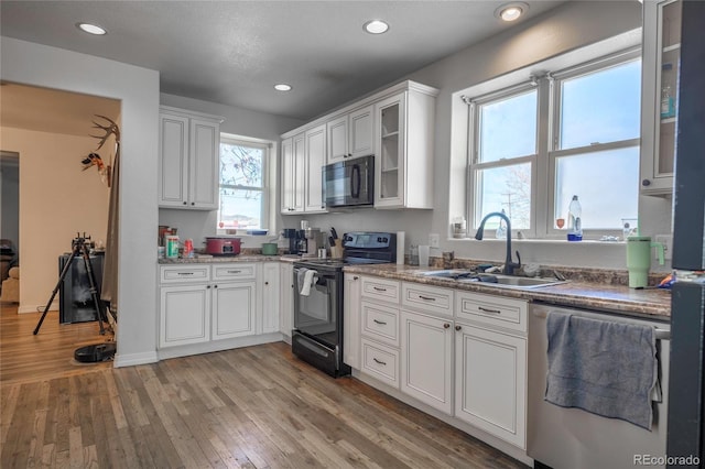 kitchen with white cabinetry, sink, light hardwood / wood-style floors, black appliances, and plenty of natural light