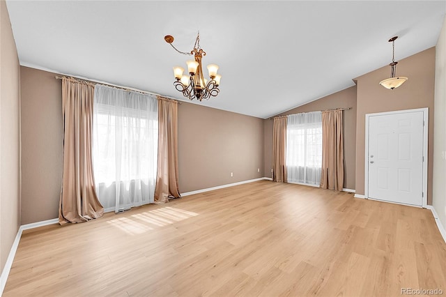 empty room with baseboards, a notable chandelier, light wood-style floors, and lofted ceiling