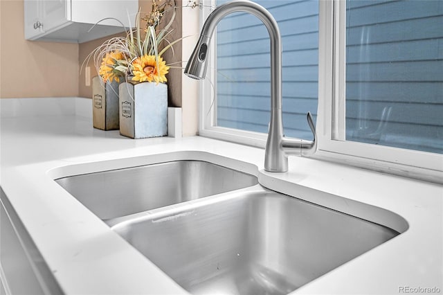 interior details featuring white cabinetry, light countertops, and a sink