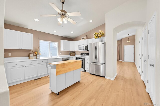 kitchen with a sink, white cabinets, arched walkways, and appliances with stainless steel finishes
