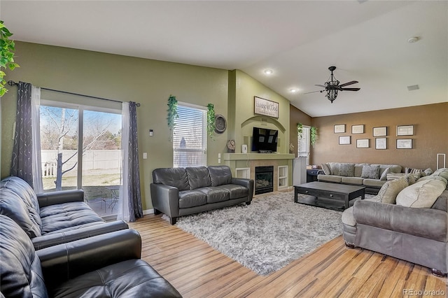 living room featuring lofted ceiling, wood-type flooring, a large fireplace, and ceiling fan