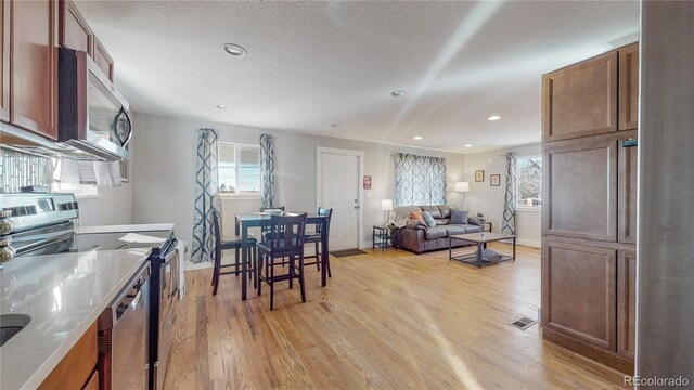 kitchen featuring light stone counters, plenty of natural light, appliances with stainless steel finishes, and light wood-type flooring