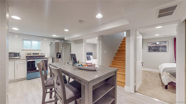 kitchen featuring decorative backsplash, light hardwood / wood-style flooring, white cabinets, and appliances with stainless steel finishes