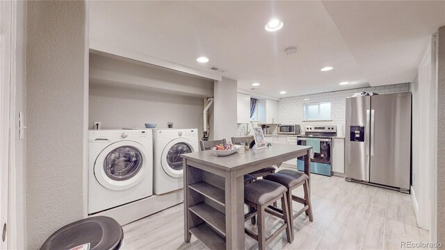 laundry room featuring light hardwood / wood-style floors and washing machine and clothes dryer