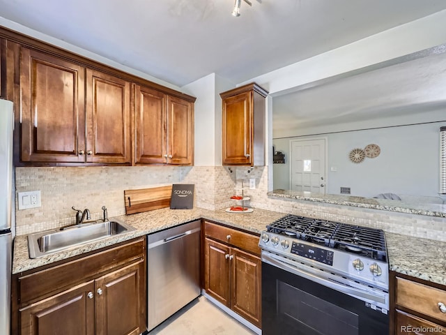 kitchen with light stone counters, appliances with stainless steel finishes, sink, and decorative backsplash