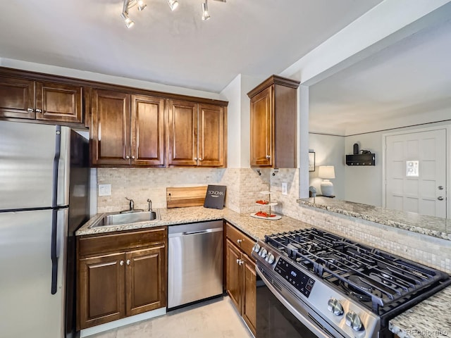 kitchen featuring tasteful backsplash, sink, light stone counters, and stainless steel appliances