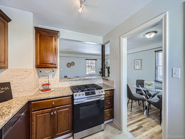 kitchen with light stone counters, decorative backsplash, light hardwood / wood-style flooring, and appliances with stainless steel finishes