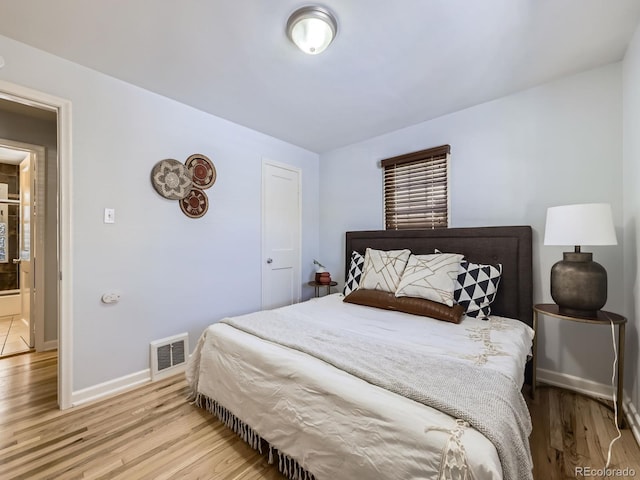 bedroom featuring connected bathroom and light wood-type flooring