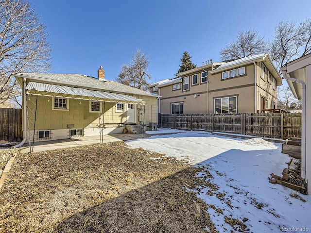 snow covered rear of property featuring a patio area