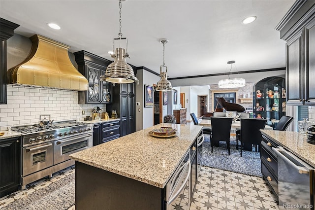 5475 S Laredo St, Centennial, CO 80015 - kitchen with appliances with stainless steel finishes, premium range hood, a kitchen island, hanging light fixtures, and decorative backsplash