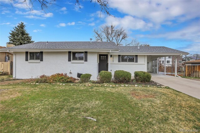 ranch-style house with brick siding, an attached carport, a front lawn, fence, and concrete driveway