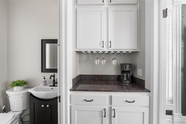 bar with white cabinetry and sink