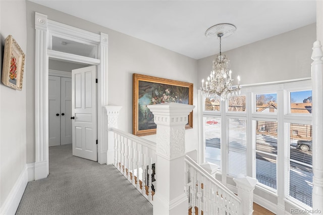 hallway featuring an inviting chandelier and carpet flooring