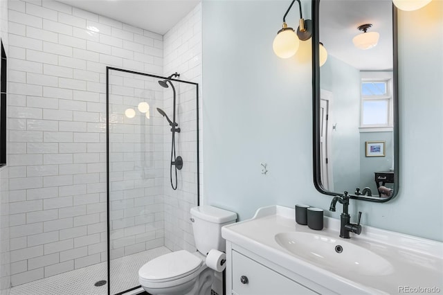 bathroom with tiled shower, vanity, and toilet