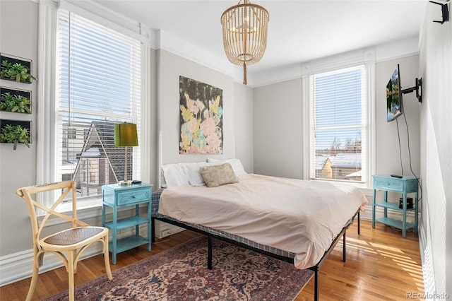 bedroom featuring hardwood / wood-style flooring, multiple windows, and a notable chandelier