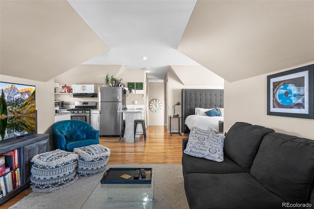 living room featuring lofted ceiling and light hardwood / wood-style floors