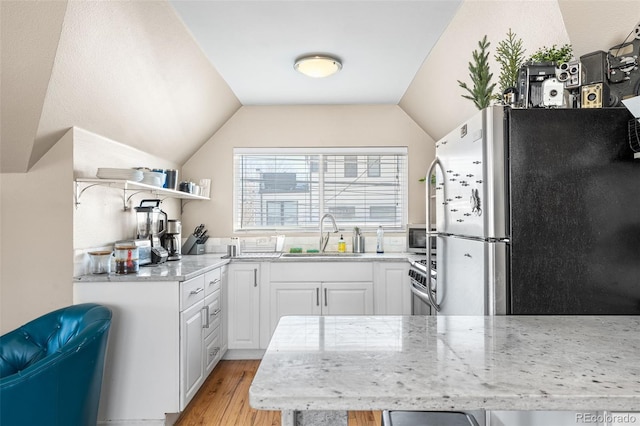 kitchen with lofted ceiling, sink, light hardwood / wood-style flooring, stainless steel appliances, and white cabinets