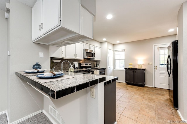 8231 S Fillmore Way, Centennial, CO 80122 - kitchen with appliances with stainless steel finishes, white cabinetry, a peninsula, a breakfast bar, and recessed lighting