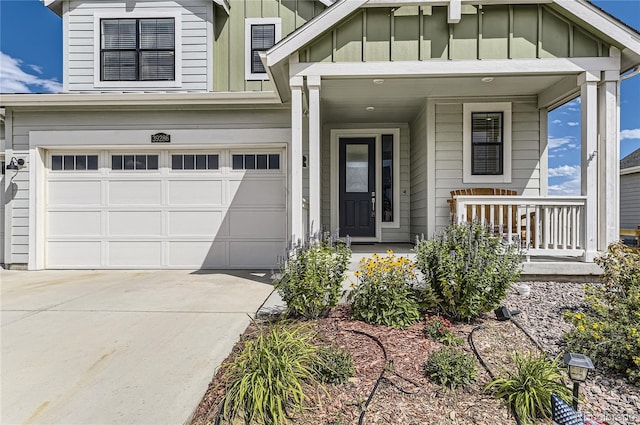 view of exterior entry with covered porch, concrete driveway, board and batten siding, and a garage