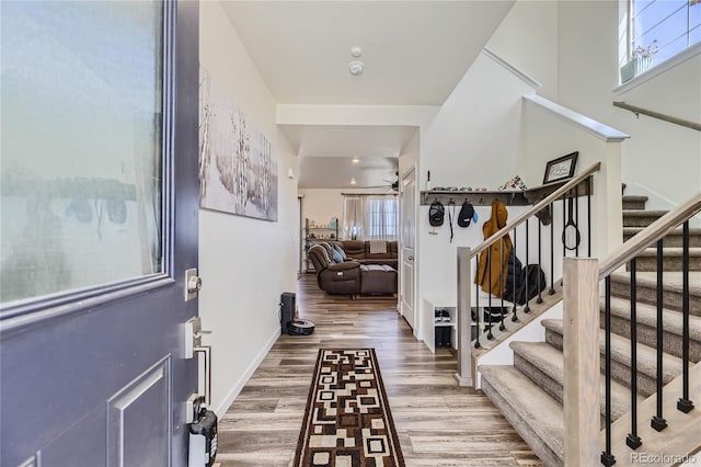 entryway with stairway, wood finished floors, a ceiling fan, and baseboards