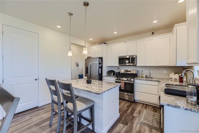 kitchen with stainless steel appliances, white cabinetry, a sink, and dark wood-style floors