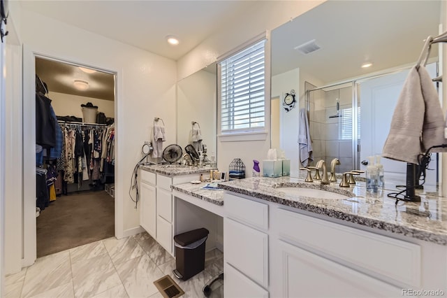 bathroom featuring visible vents, a shower stall, vanity, and a spacious closet