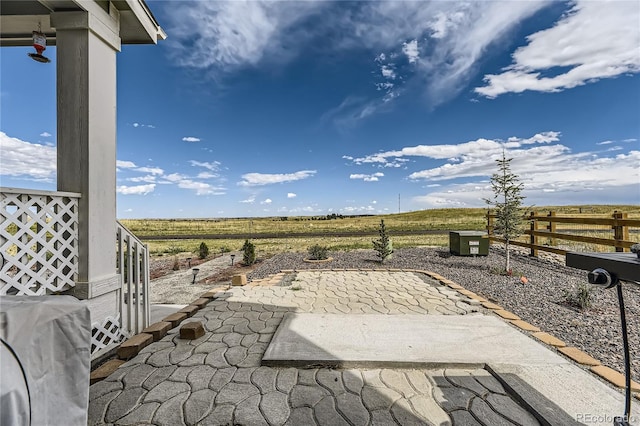 view of yard featuring a rural view, a patio area, and fence