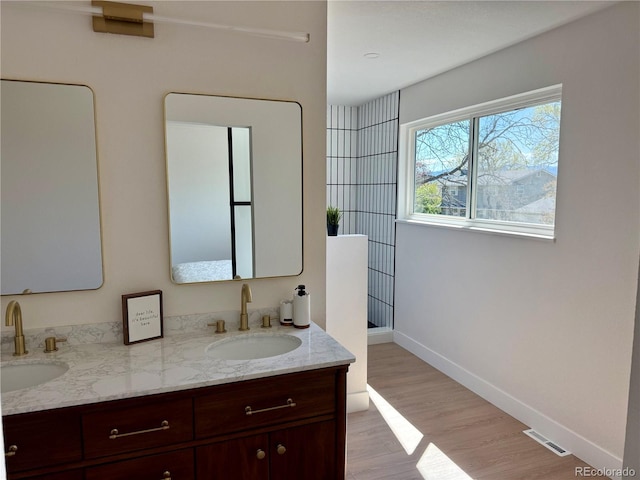 full bath featuring a sink, double vanity, visible vents, and wood finished floors